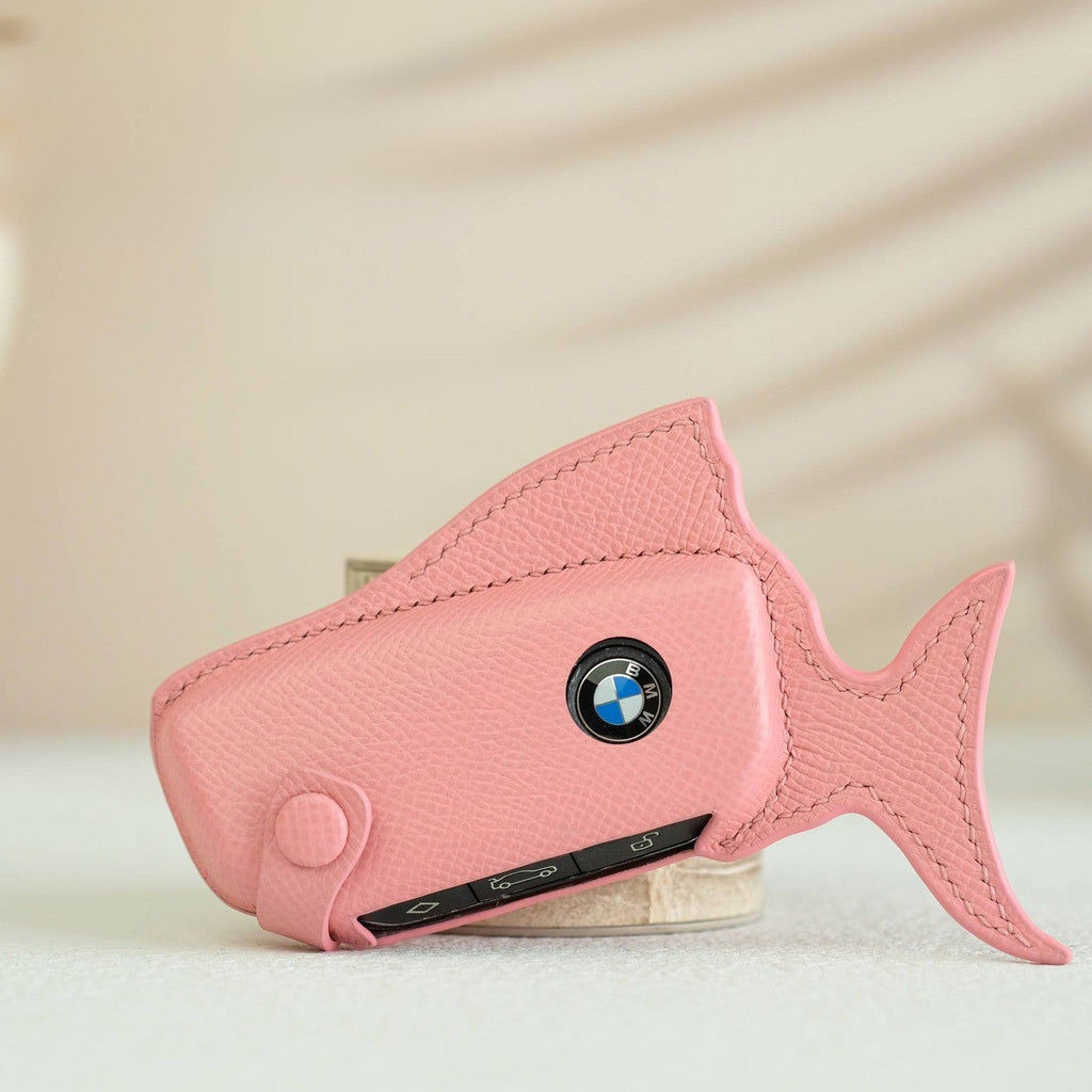 Pink fish-shaped car key case with BMW logo on a light background