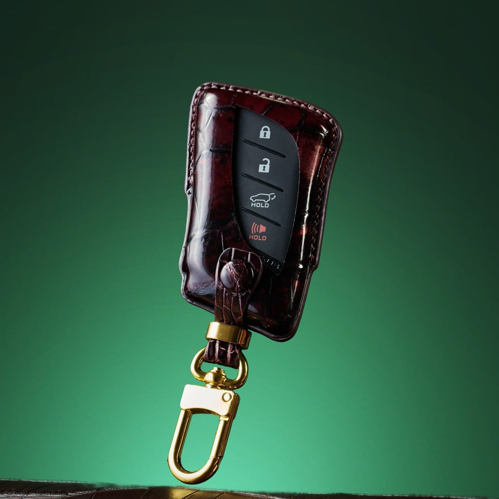 Lexus Brown leather car key case with gold clip on a green background