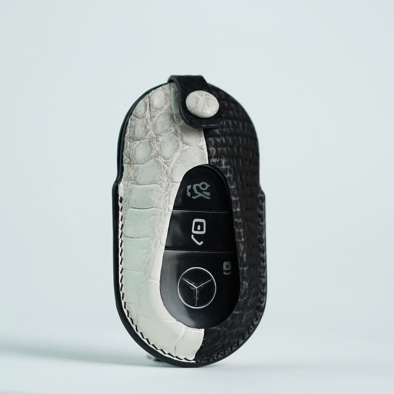 Black crocodile skin key fob cover with Mercedes-Benz logo on a light gray background